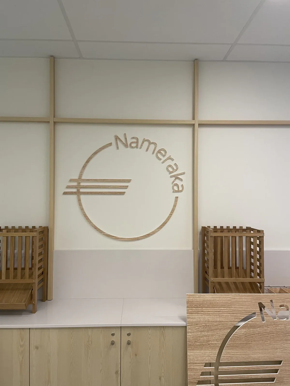 Logo mural en bois intégré à un aménagement intérieur avec mobilier assorti.
