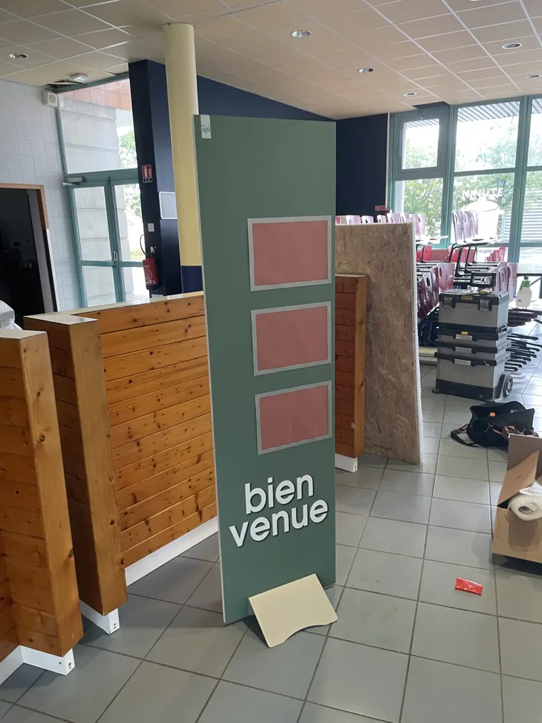 Totem de bienvenue vert et rose installé dans un espace de restauration.